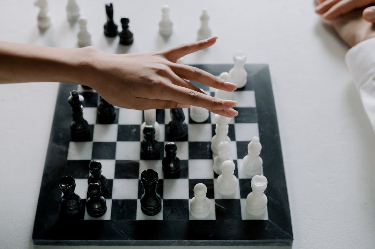 Top view of a chess match showing a hand making a strategic move indoors.